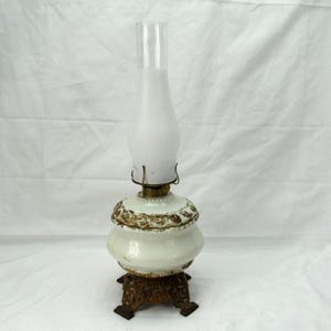 Antieke kerosineolielamp van melkglas met sierlijke metalen voet op voet