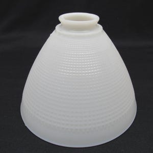 May include: A white, cone-shaped glass lampshade with a textured, dotted pattern. The lampshade has a rounded top and a flared base. The overall shape is reminiscent of a vintage design.