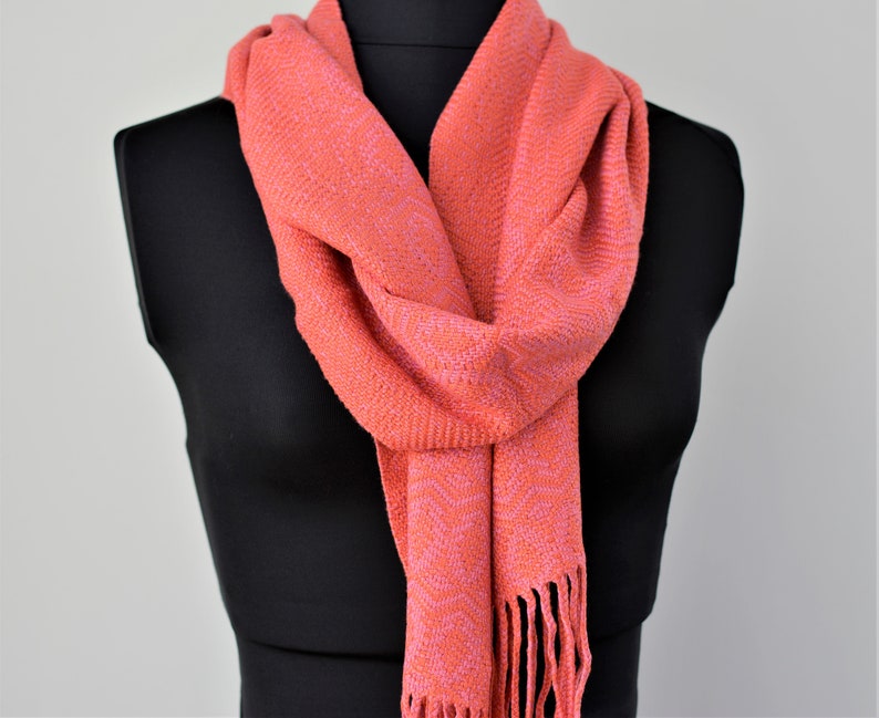 Bold coral and rose handwoven bamboo scarf with subtle fancy diamond pattern. 6.5 inches wide by 74 long, drapes beautifully. Finished with hand-braided fringe.