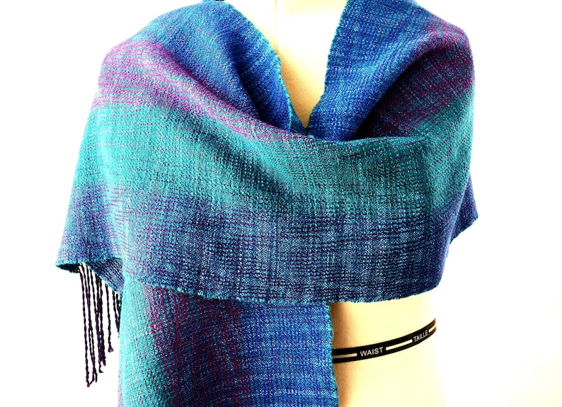 Multi-color handwoven Tencel and Alpaca Scarf. Warp colors include Iris, Amethyst, Red-Violet, Teal Green tencel in broad, blended stripes. Hand-painted soft alpaca in shades of blue and green form the weft. Size is 13.75 inches wide by 70 inches long.Finished with a hand twisted fringe. Hand wash warm, lay flat to dry.