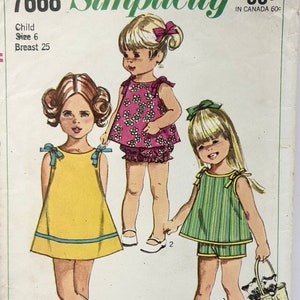Puede incluir: Patrón de costura vintage Simplicity número 7668 para un vestido de niña. El patrón incluye tres estilos diferentes: un vestido amarillo con ribete azul, un vestido rosa con flores blancas y un vestido a rayas verde y blanco. El patrón es para una niña de talla 6 con una medida de pecho de 63,5 cm.