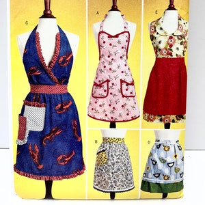 May include: A sewing pattern for five different apron designs. The aprons feature various prints, including cherries, lobsters, and chickens. The pattern is for sizes small, medium, and large.
