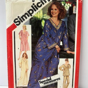 May include: A white ceramic mug with a black handle and the text "But First, Coffee" in a bold, black font. The mug is set against a blurred background, suggesting a cozy setting. The mug appears to be approximately 4 inches tall.