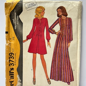 Op de afbeelding: Vintage McCall's 3739 naaipatroon voor damesjurk of kaftan. De patroonhoes toont illustraties van twee jurken, één rood en één gestreept in oranje, paars en geel. De hoes is vergeeld en bevat de tekst "Extra Carefree".