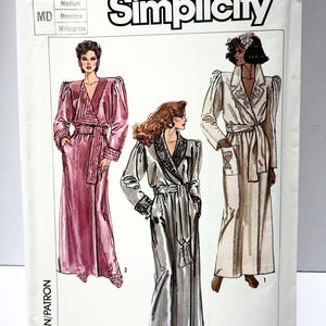 May include: Simplicity sewing pattern number 7186 for a long robe with a shawl collar and sash. The pattern includes three different versions of the robe: one in pink, one in silver, and one in white.