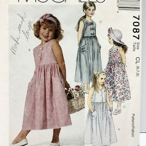 May include: A sewing pattern for making three girls' dresses. The pattern is for sizes 6, 7, and 8. The dresses are all sleeveless and have a simple, classic design. The pattern is from McCall's and the pattern number is 7087.