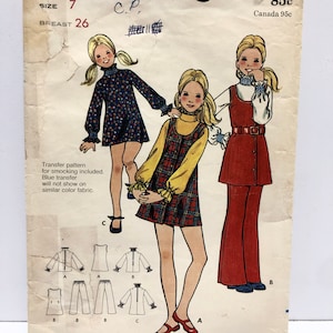 May include: A vintage sewing pattern for girls' clothing. The pattern is for sizes 7-14 and includes three different styles: a dress with a Peter Pan collar, a jumper with a plaid skirt, and a jumpsuit with a wide-legged pant. The pattern is from Butterick and is number 6298.