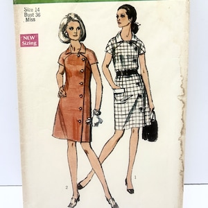 May include: Vintage Simplicity sewing pattern number 8735 for a dress. The pattern is for size 14, bust 36, and is for misses. The pattern shows two women wearing different versions of the dress. One dress is a solid orange color and the other is a plaid pattern.