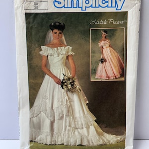 May include: A Simplicity 6766 sewing pattern envelope for a wedding dress. The front shows a white off-the-shoulder gown with ruffled sleeves and lace trim, plus an inset photo of a pink version. The text includes Simplicity, 6766, 10, Eur 38, and Michele Piccione.