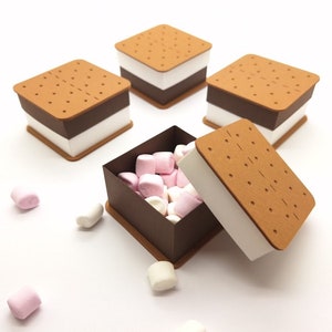 Op de afbeelding: Vier bruine en witte dozen in de vorm van marshmallows met een open doos gevuld met roze en witte marshmallows.