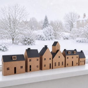 Könnte beinhalten: Eine Reihe von sechs Miniaturhäusern aus braunem Karton mit schwarzen Dächern sowie ausgeschnittenen Fenstern und Türen. Die Häuser variieren in Höhe und architektonischer Form, wobei eines ein Zifferblatt auf der Vorderseite hat, auf einem weißen Sims.