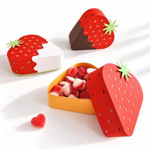 May include: Three strawberry-shaped paper boxes in red with yellow seed patterns and green leaf accents. One box is open, revealing heart-shaped red and white gummy candies inside. Another box is dipped in white, and one is dipped in dark brown.