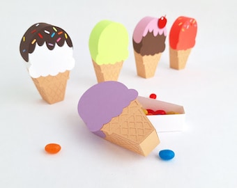 May include: A set of five ice cream cone shaped boxes, four are filled with colorful candies and one is empty. The boxes are made of paper and are decorated with different colors and designs. The boxes are perfect for holding small gifts or treats.