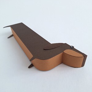 May include: A brown and tan paper dachshund, a paper craft.