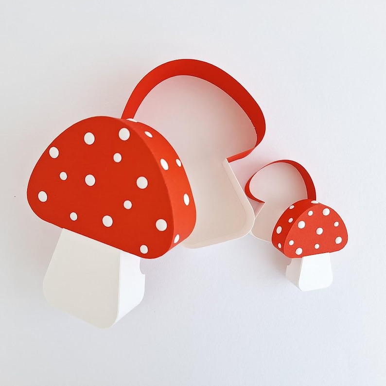 Pode incluir: Duas caixas em forma de cogumelo vermelho e branco com bolinhas brancas. A caixa maior est&aacute; aberta e a menor est&aacute; fechada.