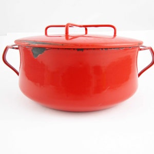 May include: Red enamel pot with a lid and two handles. The pot has a slightly rounded shape and a black enamel interior.