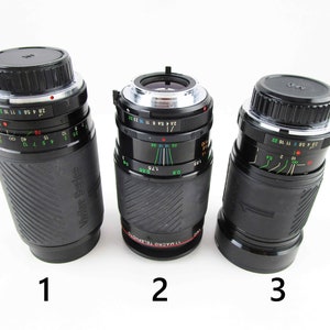 May include: Three black camera lenses with silver rings and markings. The lenses are labeled 1, 2, and 3. The lens labeled 2 has the text "77 MACRO TELEPHOTO" printed on it.