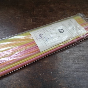 Könnte beinhalten: Eine Packung bunter Plastik-Trinkhalme in Gelb, Rosa und Orange. Die Packung ist mit "KONTROLLIEREN SIE DIE MISCHUNG" und "STREICHHOLZER" beschriftet.