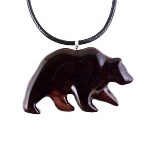 A dark reddish-brown bear pendant necklace. The pendant is carved in the shape of a bear and is suspended from a black cord. The bear pendant has a glossy finish and a wood grain pattern.