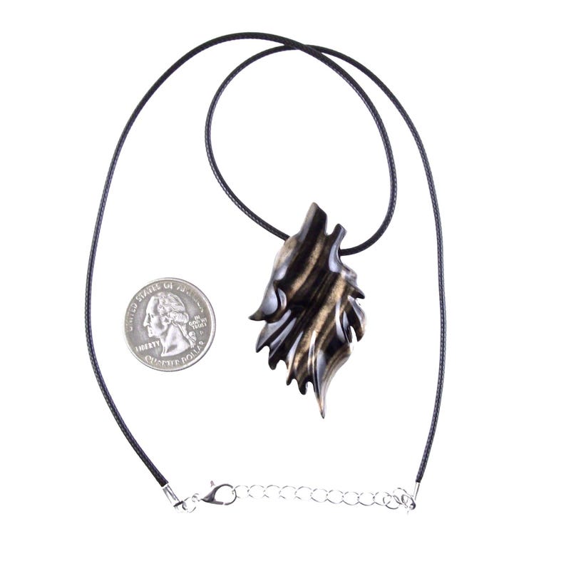 A wooden wolf head pendant necklace in black with brown streaks wood grain with glossy finish. The pendant is hanging from a black cord and a silver chain.
