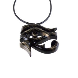 A wooden pendant necklace in black and brown, with a intricate design and a glossy finish. The pendant is shaped like an Eye of Horus and hangs from a black cord.