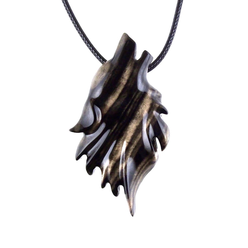 A wooden wolf pendant necklace with a black cord. The pendant is carved in the shape of a wolf's head and is black with brown streaks in color.