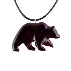 A dark reddish-brown bear pendant necklace. The pendant is carved in the shape of a bear and is suspended from a black cord. The bear pendant has a glossy finish and a wood grain pattern.