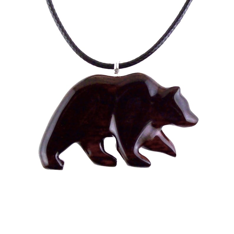 A dark reddish-brown bear pendant necklace. The pendant is carved in the shape of a bear and is suspended from a black cord. The bear pendant has a glossy finish and a wood grain pattern.