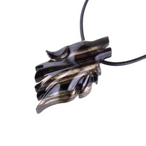 A black with brown streaks wooden pendant shaped like a wolf head with a black cord.