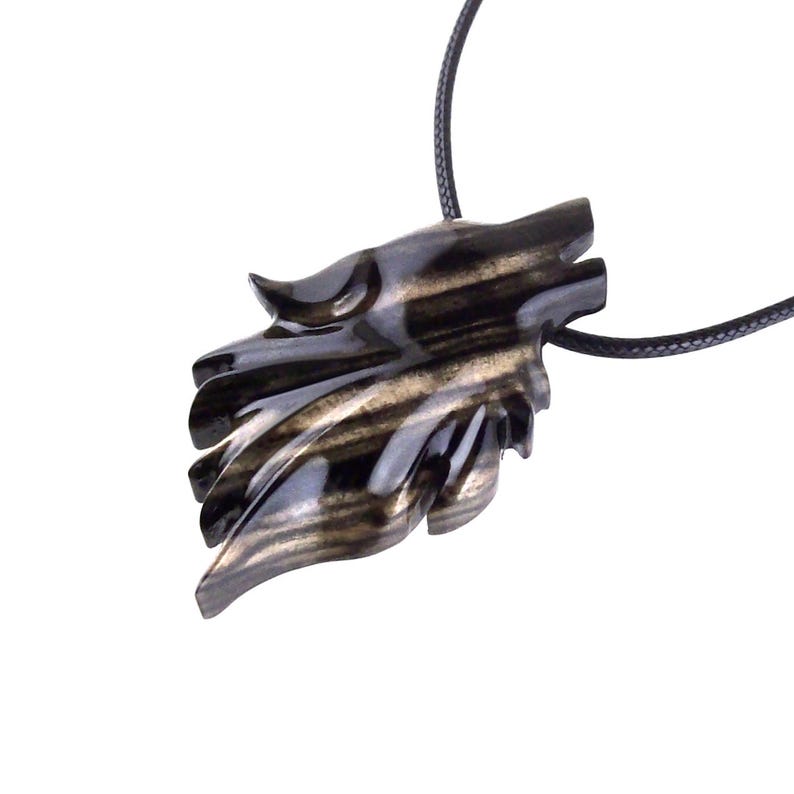A black with brown streaks wooden pendant shaped like a wolf head with a black cord.
