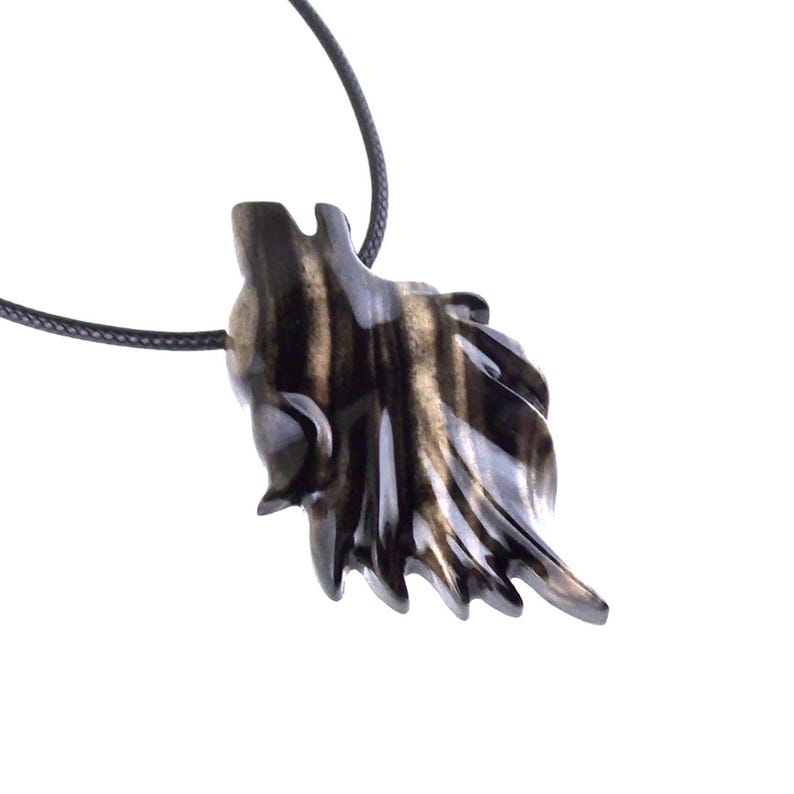 A black with brown streaks wooden wolf pendant necklace on a black cord. The pendant is intricately carved and has a detailed wolf head design.