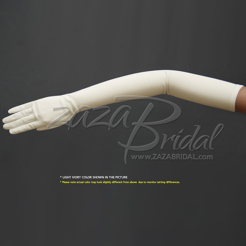 May include: A pair of long, ivory-colored gloves. The gloves are made of a smooth, stretchy material and extend to the elbow. The gloves are shown on a model's arm, bent at the elbow.