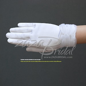 May include: White satin gloves with a ruffled wrist detail and small rhinestones. The gloves are shown on a hand with the fingers extended.