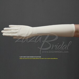 May include: A pair of long, ivory-colored satin gloves. The gloves are shown on a hand, with the fingers extended. The gloves are smooth and have a slight sheen.