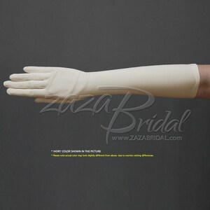 May include: Ivory long satin gloves, extending to the elbow. The gloves are shown on a hand, with the fingers extended. The text "Zaza Bridal" and "www.ZAZABRIDAL.com" is visible below the hand. The text "IVORY COLOR SHOWN IN THE PICTURE" is visible below the text. The text "Please note actual color may look slightly different from above due to monitor setting differences." is visible below the text.