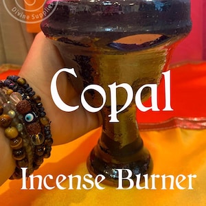 May include: A black and brown ceramic incense burner with a hole in the side. The burner is labelled "Copal Incense Burner".