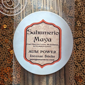 May include: A package of brown incense sticks with a white label that reads "Sahumerio Maya" and "AUM POWER Incense Sticks" with the website mangomantras.com. The label has a red border and a decorative design.