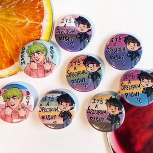 Puede incluir: Diez botones redondos con un personaje de dibujos animados con cabello verde y el texto "It's a Spectrum, Right?" y "Dream Boy". Los botones son de varios colores, incluyendo morado, azul, amarillo y verde.