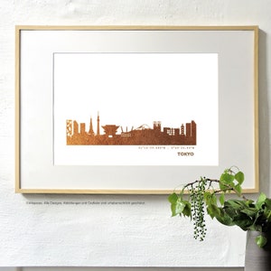 Könnte beinhalten: Ein gerahmter Druck der Skyline von Tokio in Kupferfolie. Der Druck ist auf weißem Papier und enthält die Koordinaten von Tokio. Der Text "TOKYO" ist unter der Skyline gedruckt.