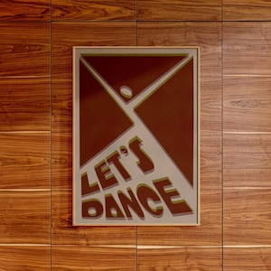 Peut inclure: Une affiche encadrée avec un fond brun et un motif géométrique. Le texte "LET'S DANCE" est écrit dans une police audacieuse et stylisée en vert et brun.