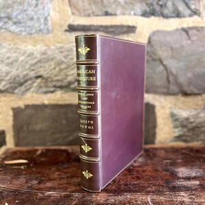 May include: A burgundy leather-bound book titled "American Furniture: Queen Anne and Chippendale Periods" by Joseph Downs.