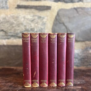 May include: A set of six vintage books from the American Statesmen series, featuring deep red covers with gold-stamped lettering on the spines. The titles include works on William Henry Seward, Charles Sumner, Henry Clay, and Thaddeus Stevens.