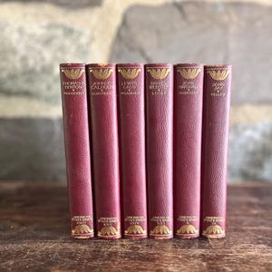 May include: A set of six maroon hardcover books from the American Statesmen series, featuring gold-embossed lettering on the spines. The titles include Thomas H. Benton, John C. Calhoun, Lewis Cass, Daniel Webster, John Marshall, and John Jay.
