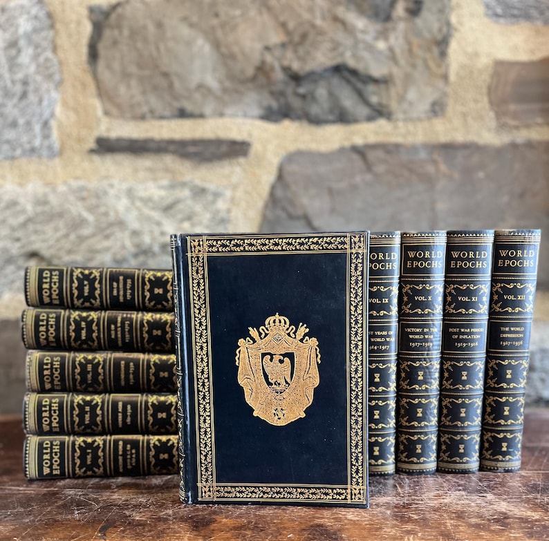 May include: A collection of antique books with dark blue covers and gold lettering. The books are titled "World Epochs" and feature decorative gold accents and a gold emblem on the front cover. The books are arranged on a wooden surface.