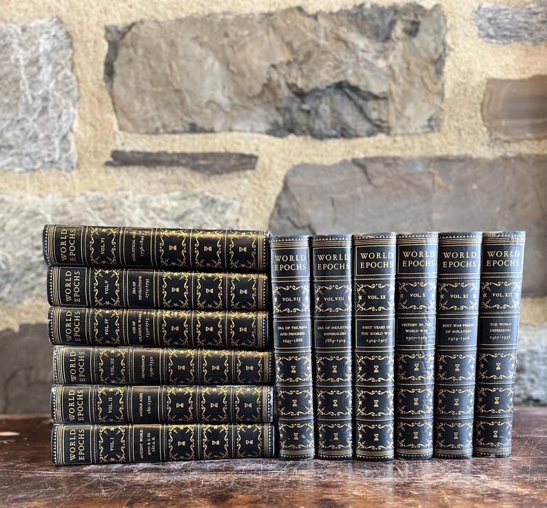 May include: A collection of antique books titled "World Epochs" with black covers and gold lettering. The books are stacked and arranged on a wooden surface against a stone wall background. The spines display volume numbers.