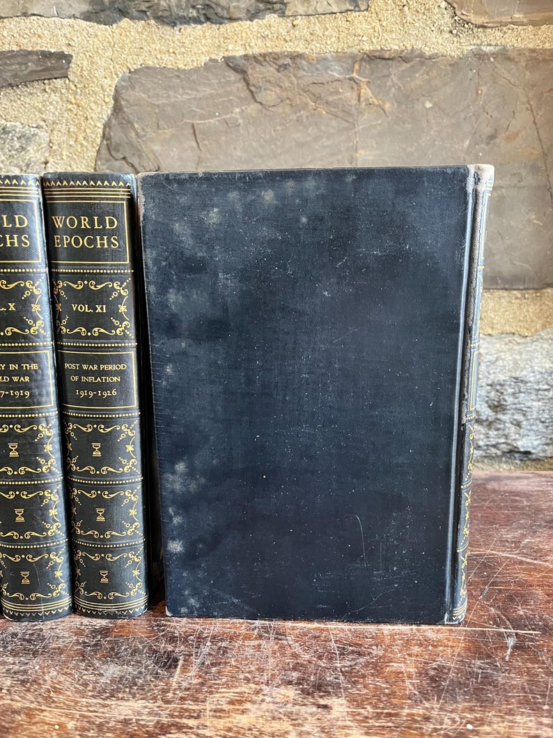 May include: A collection of antique books with black covers and gold lettering. The spines display the titles "WORLD EPOCHS" and "POST WAR PERIOD OF INFLATION". The books are arranged on a wooden surface, suggesting a vintage or historical theme.