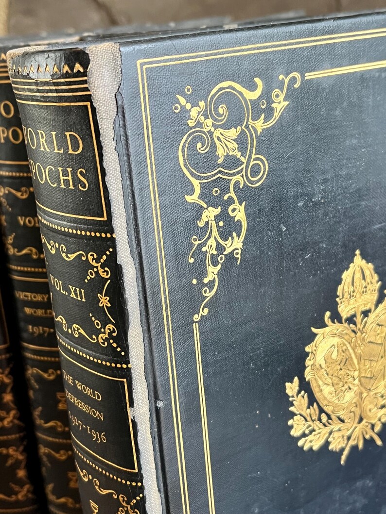 May include: Close-up of antique books with black covers and gold lettering and embellishments. The spines display titles like "World Epochs" and "The World Depression 1927-1936". The covers feature ornate gold designs.