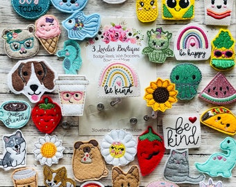 May include: A collection of colorful felt patches featuring various designs, including animals, food, and inspirational messages. The patches are perfect for adding a personal touch to bags, jackets, or other accessories.  The patches include a rainbow with the words "be kind", a sunflower, a watermelon, a taco, a cat, a dinosaur, a unicorn, a donut, a coffee cup, a strawberry, a dog, a fish, a pineapple, a rainbow with the words "be happy", a jellyfish, a  ice cream cone, a  cup of cereal, a  sushi roll, a  pair of sunglasses, and a  coffee cup with the words "Just Breathe".