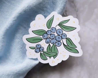 Könnte beinhalten: Ein Aufkleber mit einer Traube blauer Heidelbeeren mit grünen Blättern und gelben Punkten auf weißem Hintergrund.