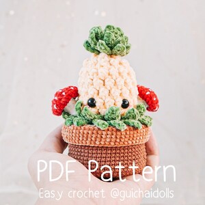 May include: A crocheted plant-like figure in a brown pot. The figure has a light yellow body, green leaves, and red and white mushroom accents. The text "PDF Pattern" and "Easy crochet @guichaidolls" are visible.
